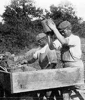 Two men mould bricks by hand.