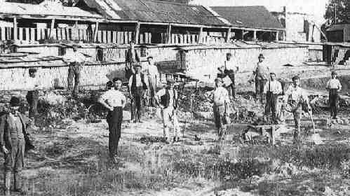 Brickworkers with their product drying in stacks behind them.