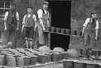 Another postcard view of the pottery as workers carry vessels outside to dry.